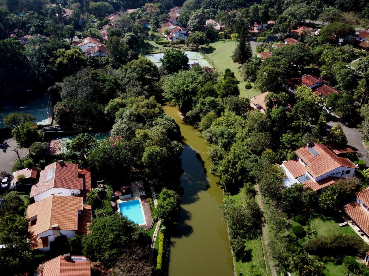 Vista aérea: o lago entre as árvores e as casas do Residence Park
